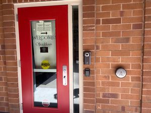 Image: Locked school office door with voice and camera entry system.